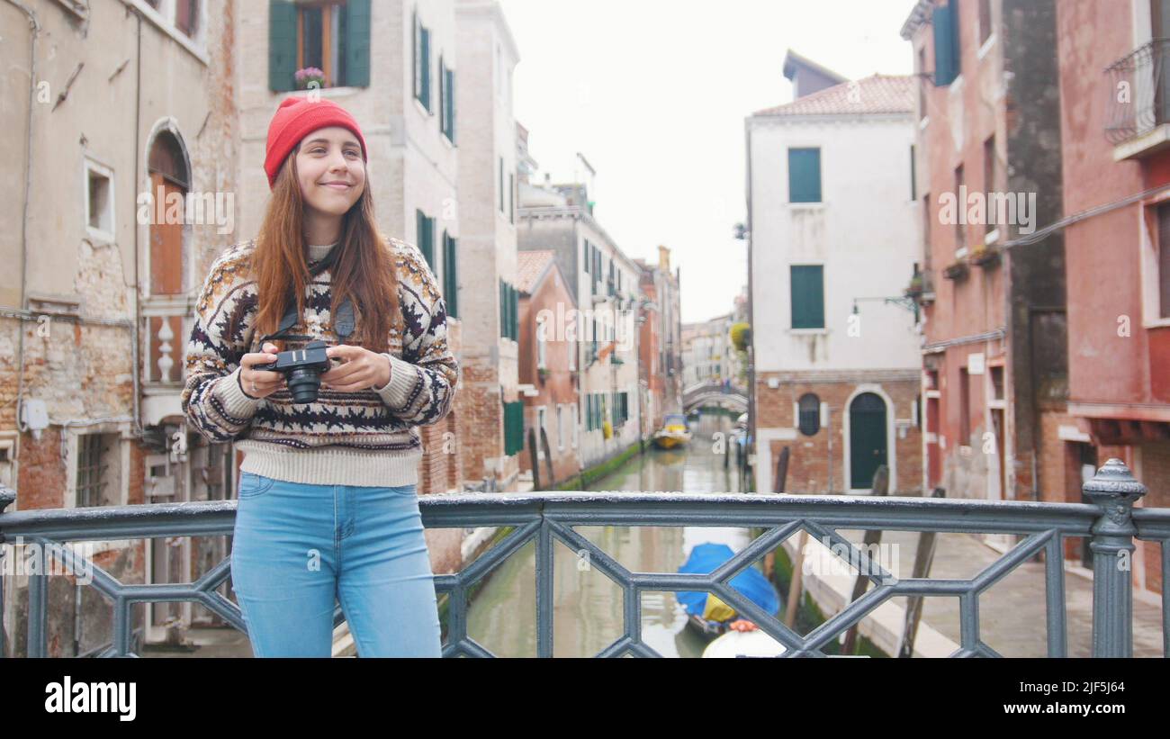 A young woman standing on the bridge holding a camera - Venice, Italy. Mid shot Stock Photo