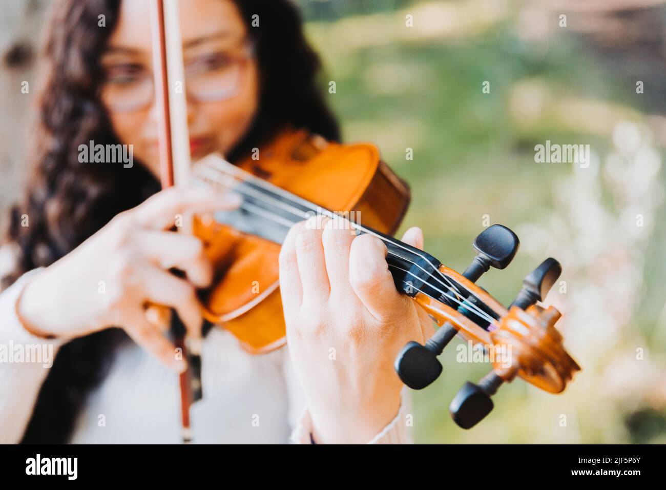 unrecognizable curly brunette woman doing pizzicato technique in violin. Selective focus. Stock Photo