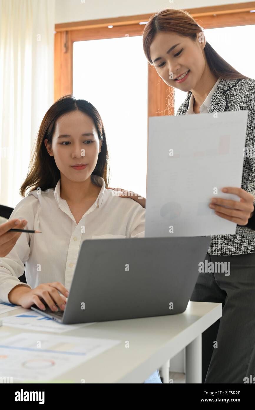 Attractive young asian female office worker or trainee working with her professional female manager in the office together. Stock Photo