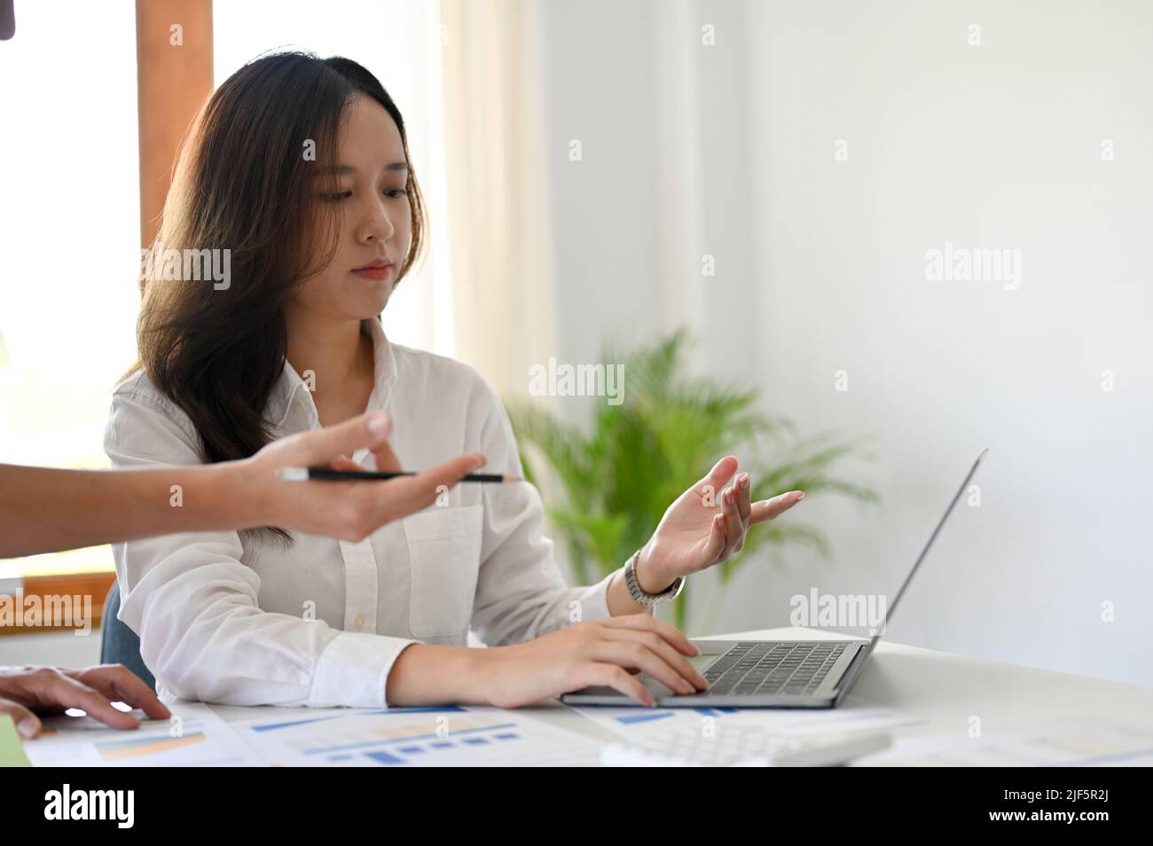 Attractive young asian female office worker or trainee working with her manager in the office, planning a campaign together. Stock Photo