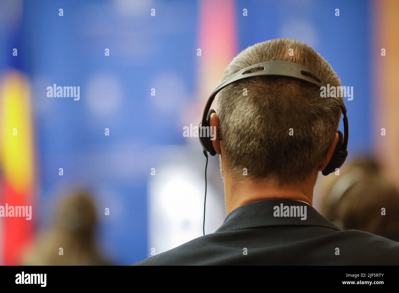 Shallow depth of field (selective focus) details with a caucasian man wearing translation headset during an international event. Stock Photo