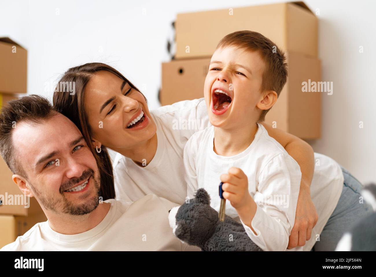 Portrait of happy family with cardboard boxes in new house at moving day Stock Photo
