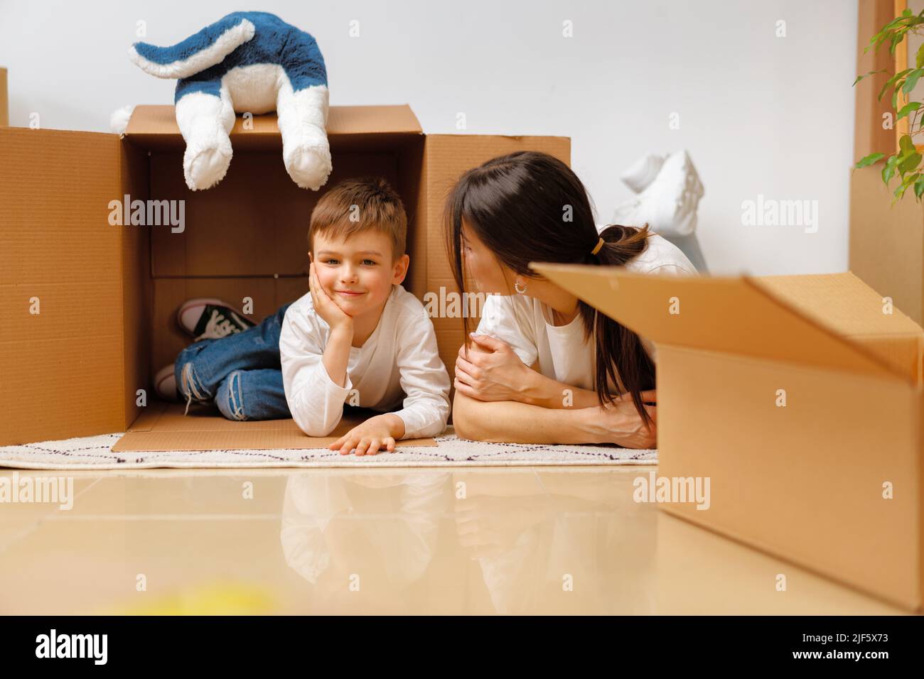 Beautiful smiling woman and little boy with cardboard boxes moving to new home Stock Photo