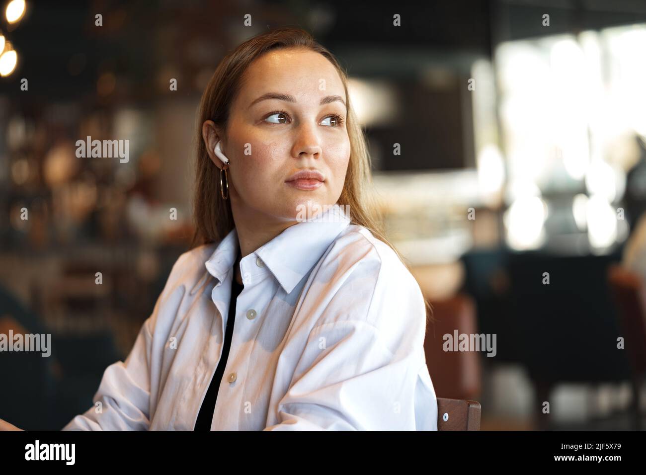Portrait of a blonde woman in white shirt sitting in cafe Stock Photo