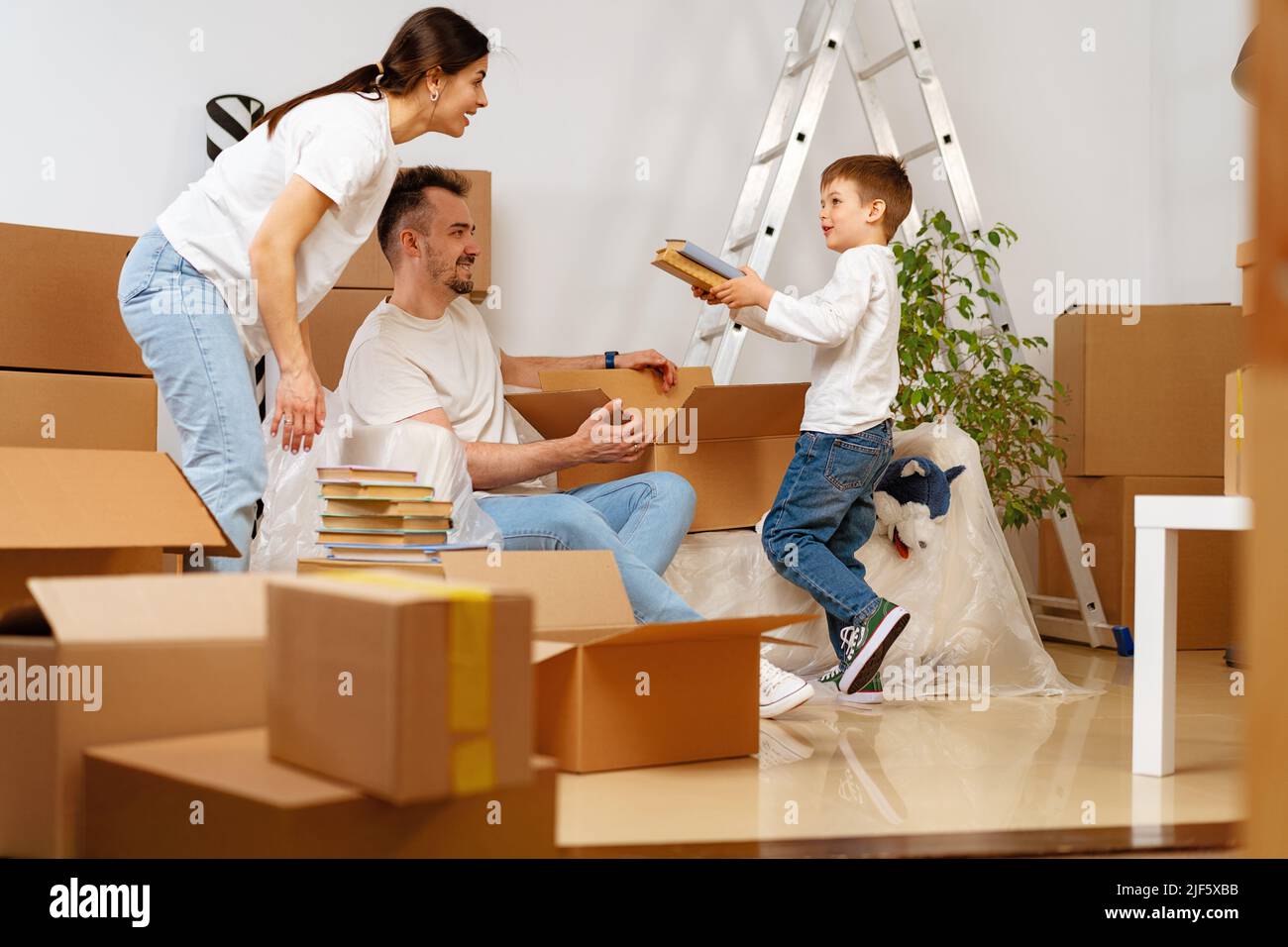 Parents and son packing boxes and moving into a new home Stock Photo