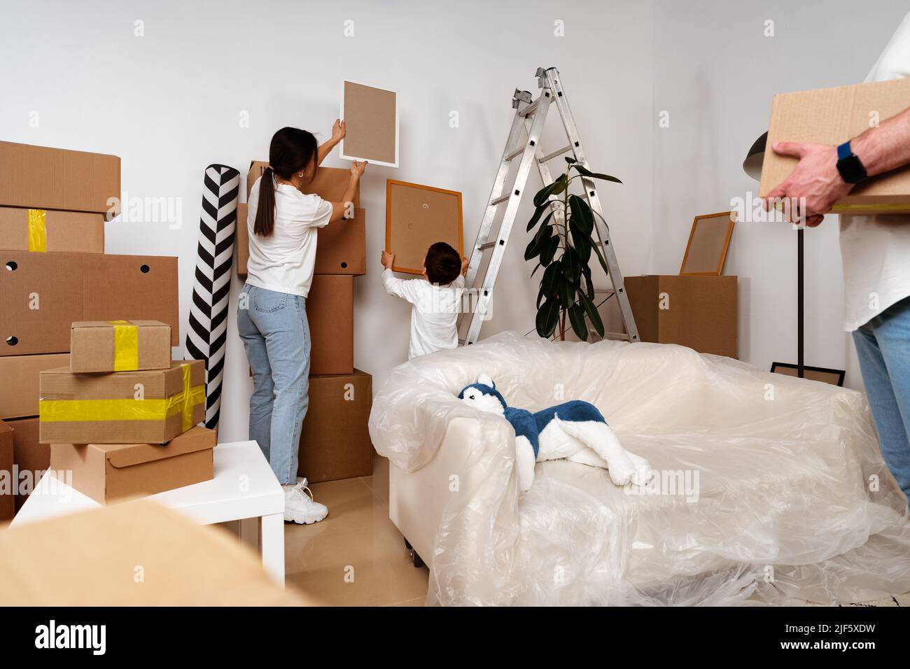 Young parents and son having fun during moving day to new house Stock Photo