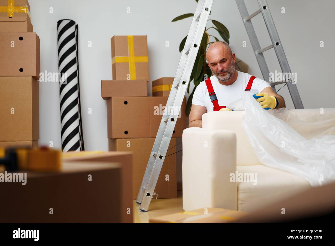 Man mover in uniiform packing sofa for relocation Stock Photo