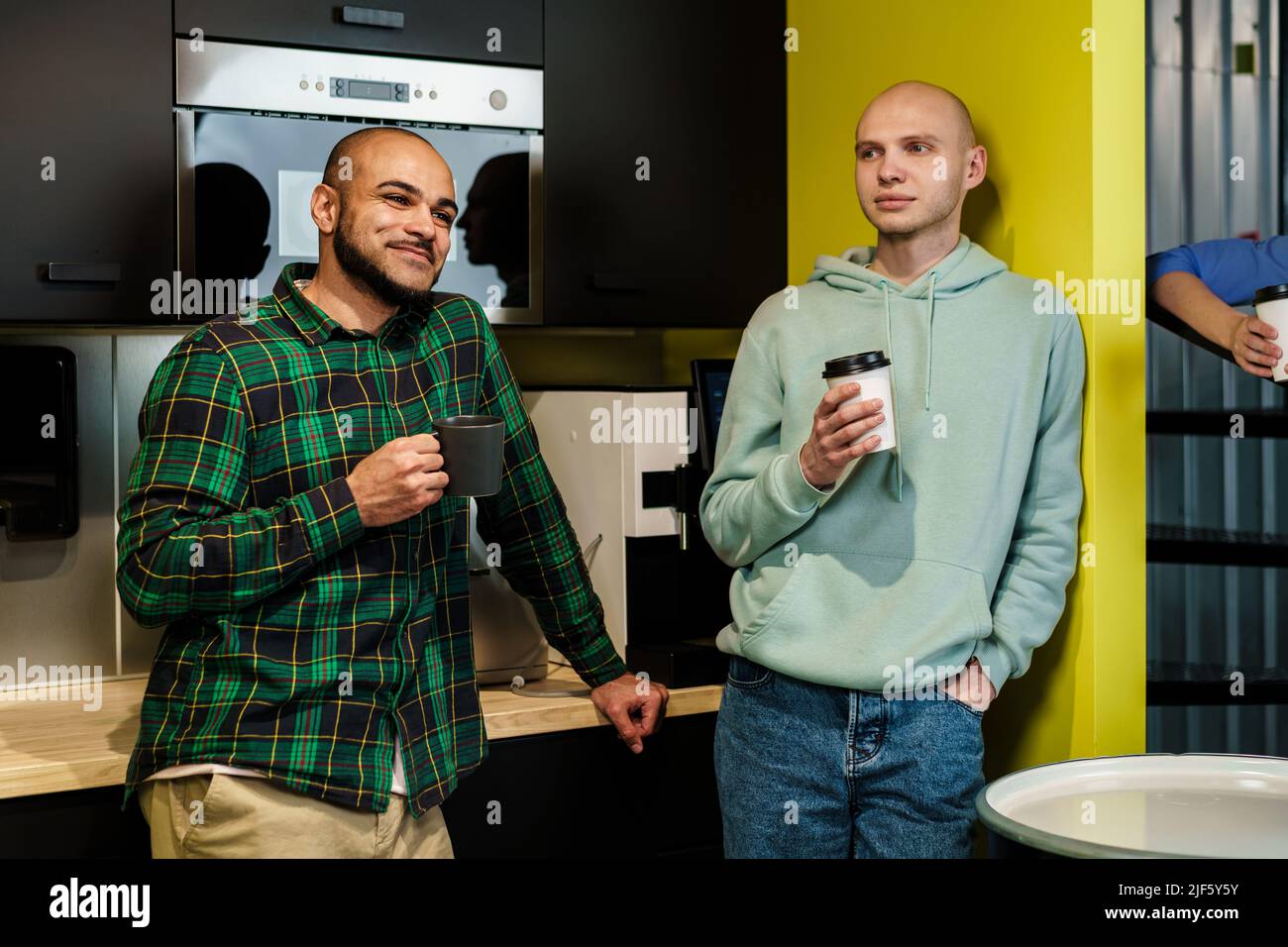 Two male colleagues having a talk while coffee break in office Stock Photo