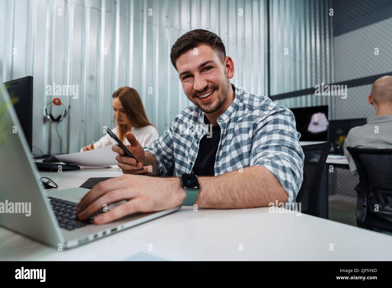 Portrait of young man sitting and working at his desk in the office. Stock Photo