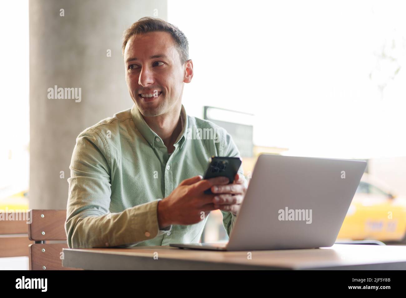 Confident businessman using smartphone sitting in restaurant Stock Photo