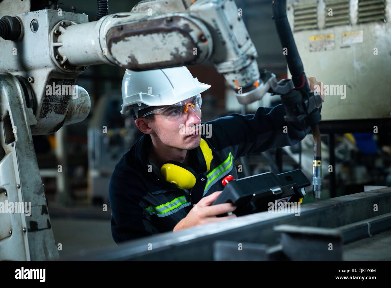 Young factory worker working with adept robotic arm in a
