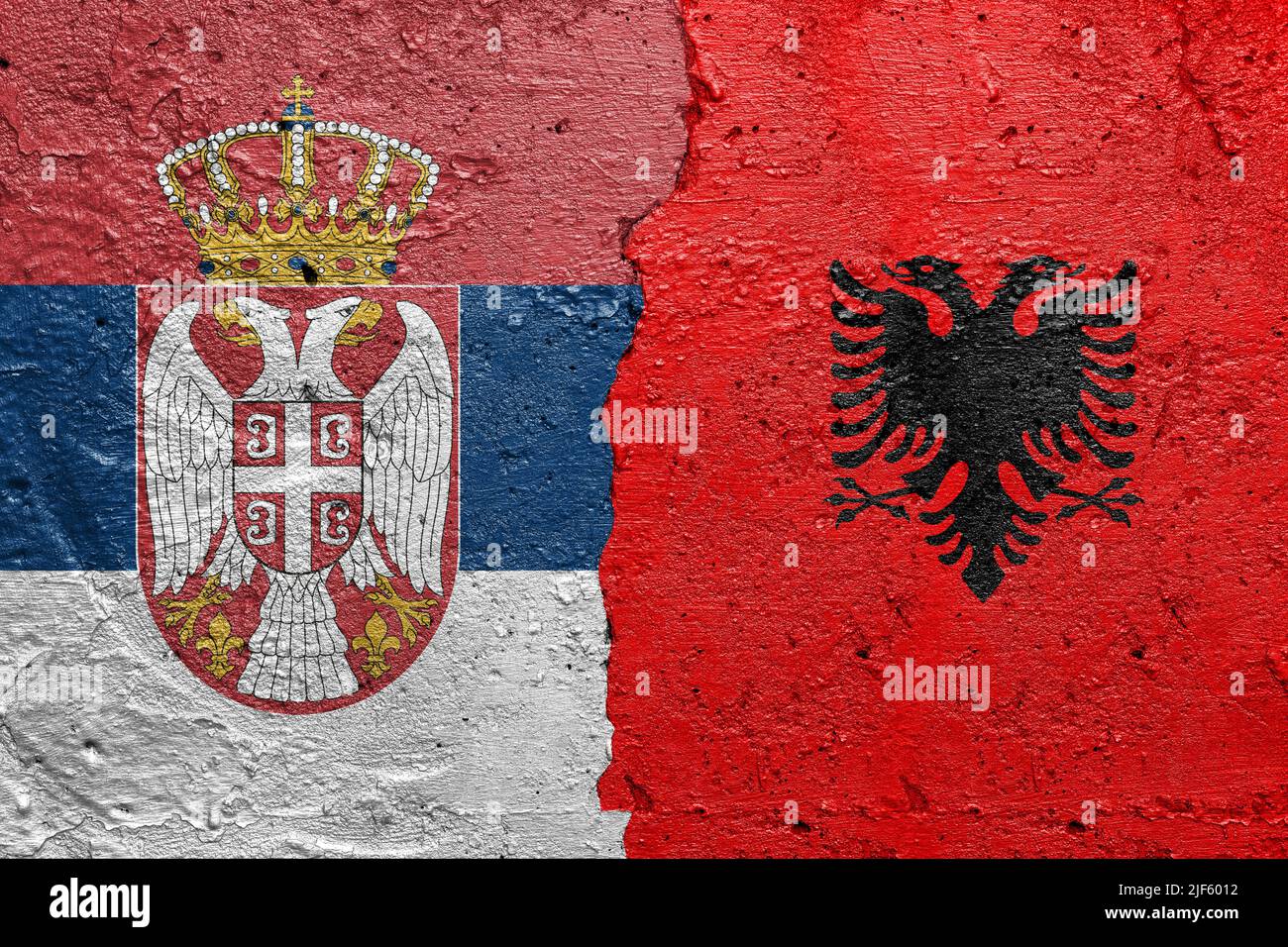 Serbia and Albania flags  - Cracked concrete wall painted with a Serbian flag on the left and a Albanian flag on the right Stock Photo