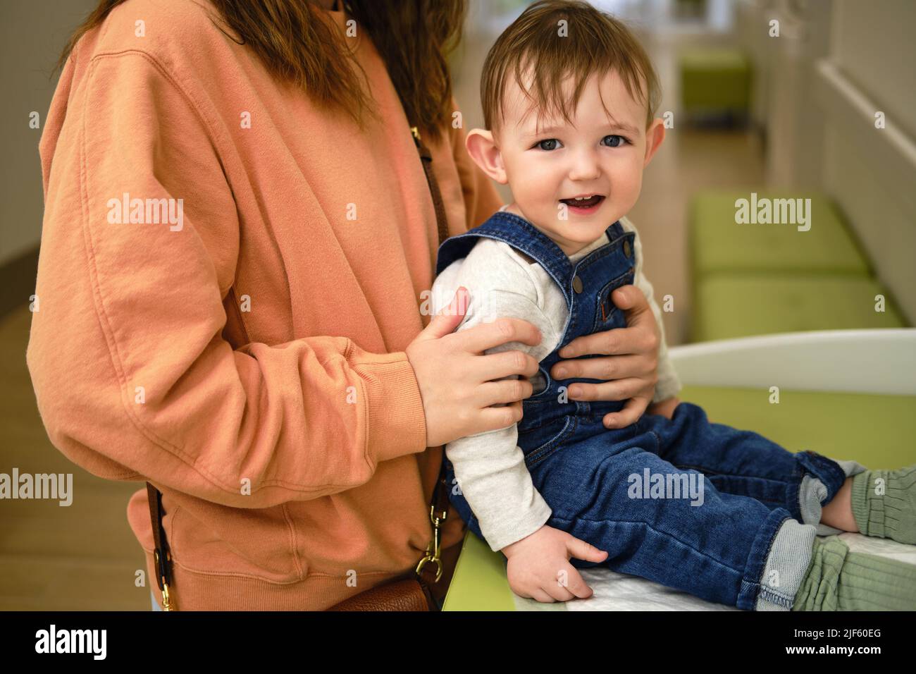 A mother woman puts clothes on a toddler baby on a changing table in