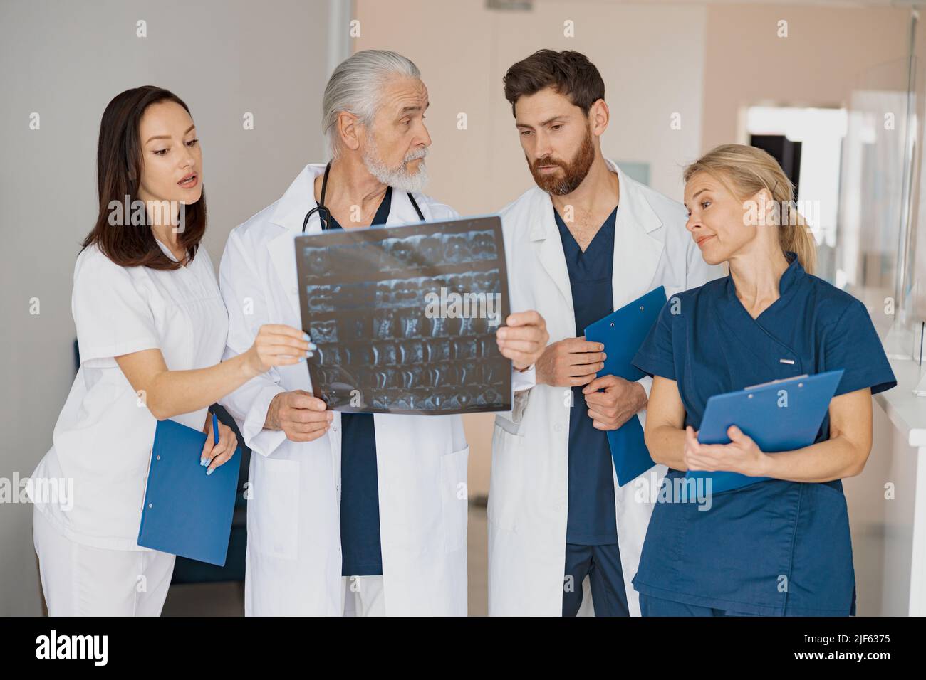Doctors In Uniform Group of doctors in uniform look and discuss an X-ray or MRI scan of ...