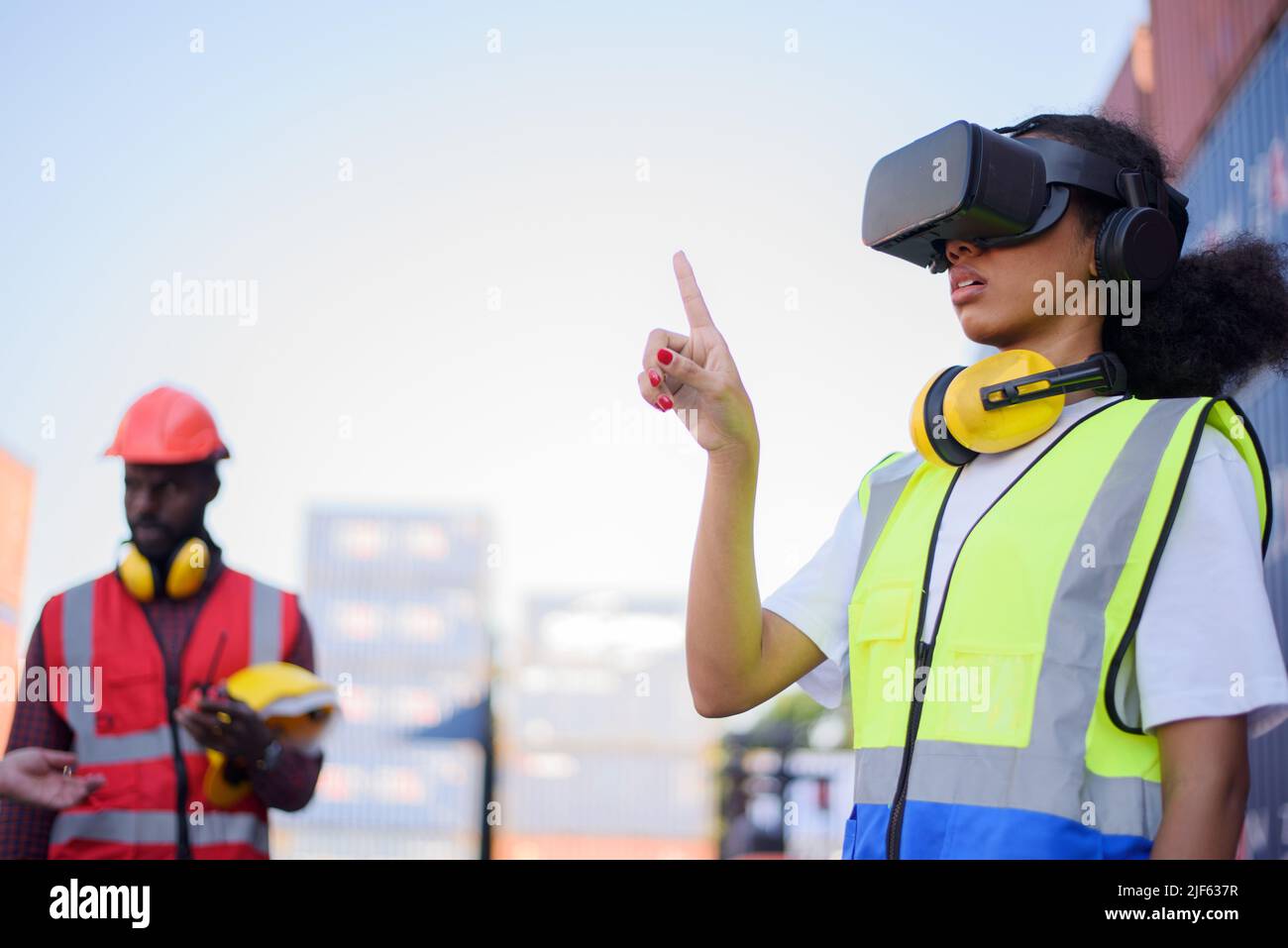 African-American female engineers wearing VR Headset look container cargo ship. Stock Photo