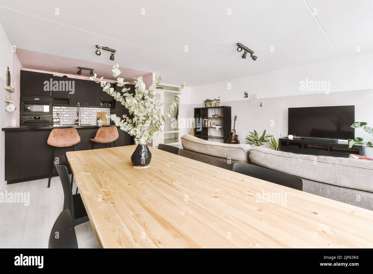 Simple interior of light living room with gray sofa in front of TV and