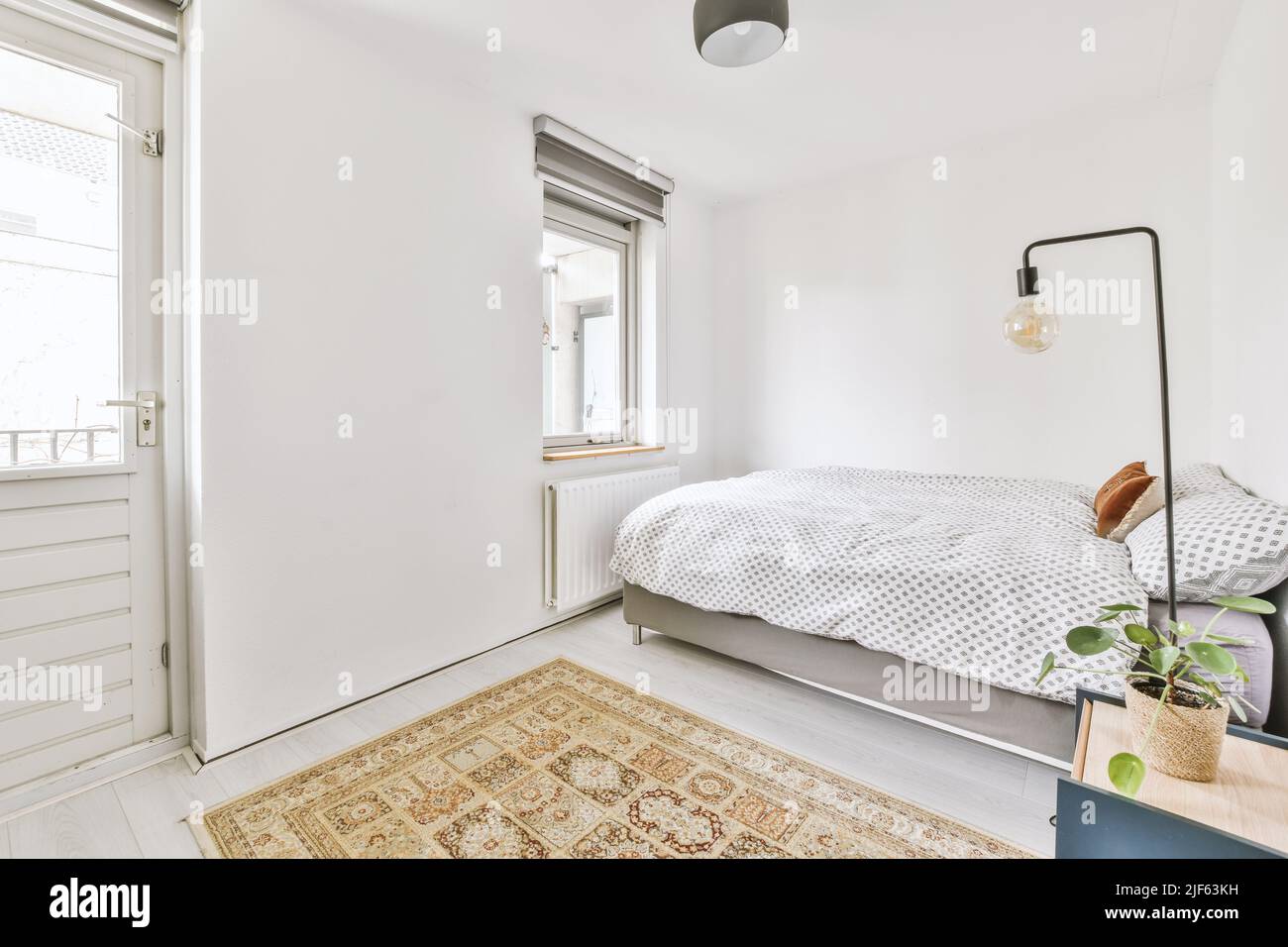 Comfortable bed and lamp placed in small narrow minimalist style