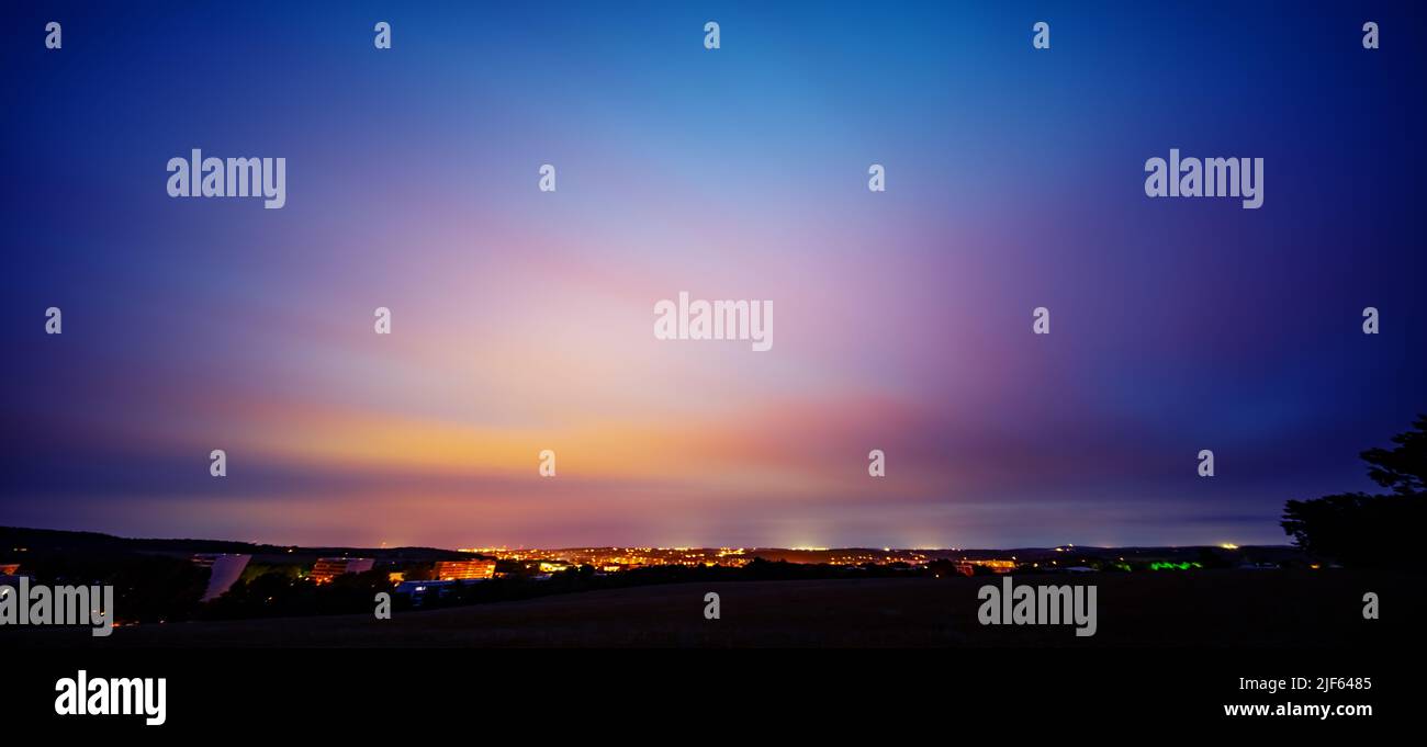 blue sky with orange clouds over the night city Stock Photo