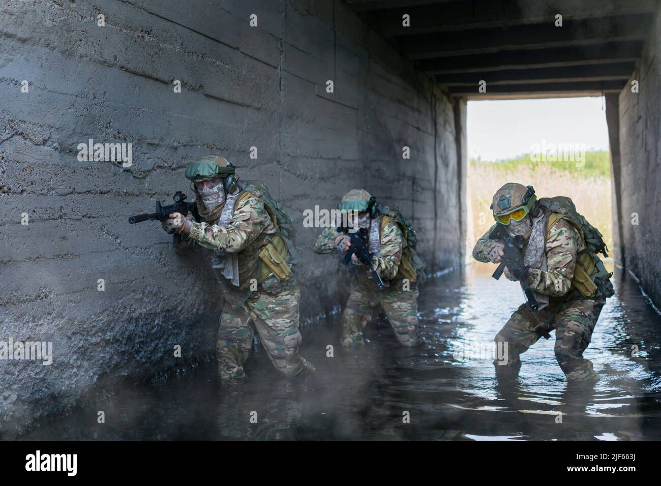 Three military mercenaries during special operation in underground bunker. Collage - one model in three poses. Focus on the left soldier. Stock Photo