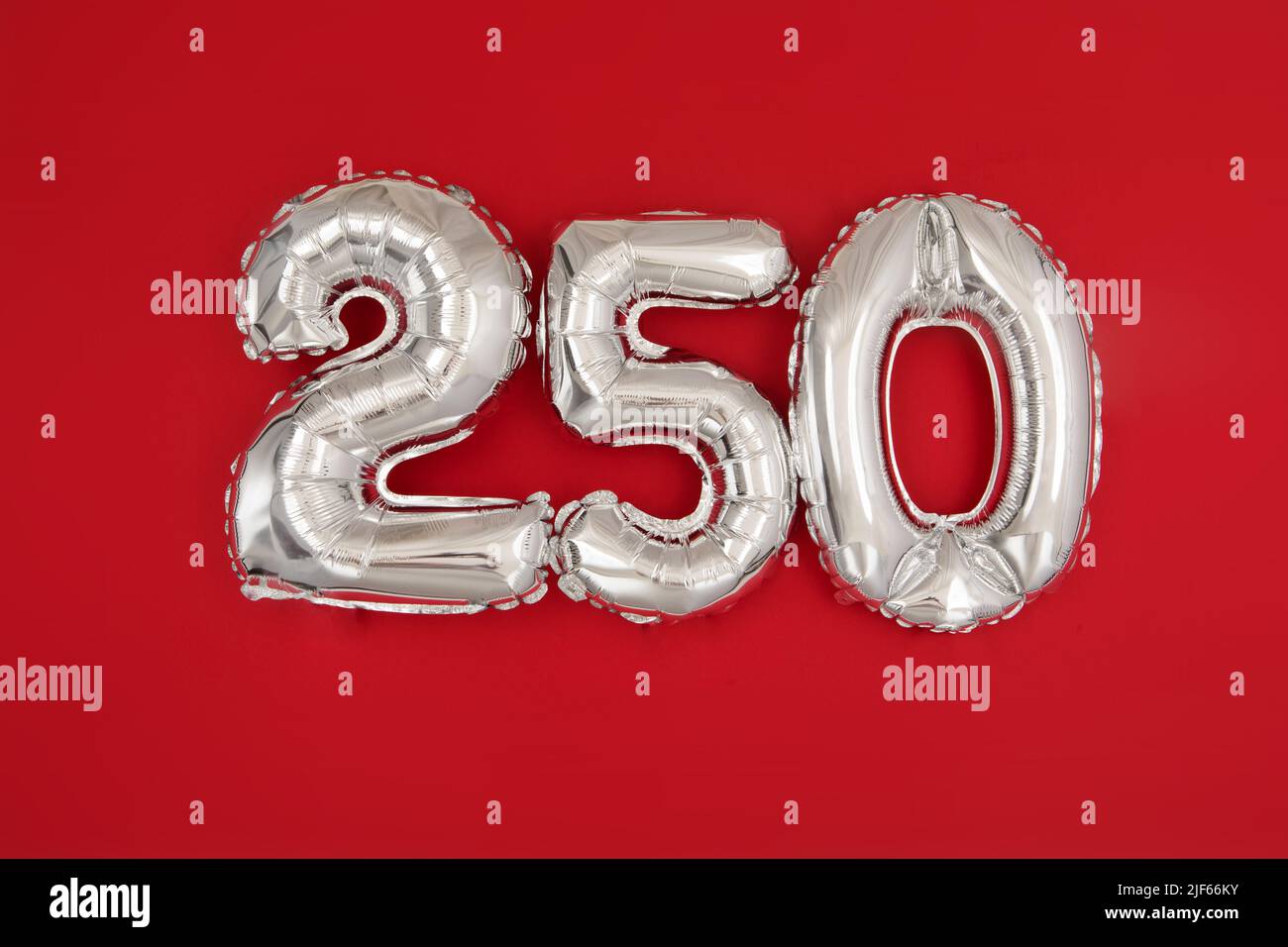 Silver balloon showing number 250 on red background Stock Photo