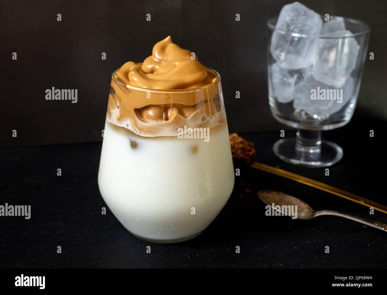 Dalgona coffee. Korean style coffee ice drink on dark background