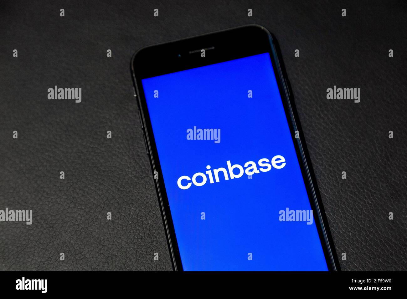 Logo of Coinbase crypto exchange on a phone screen against leather background Stock Photo