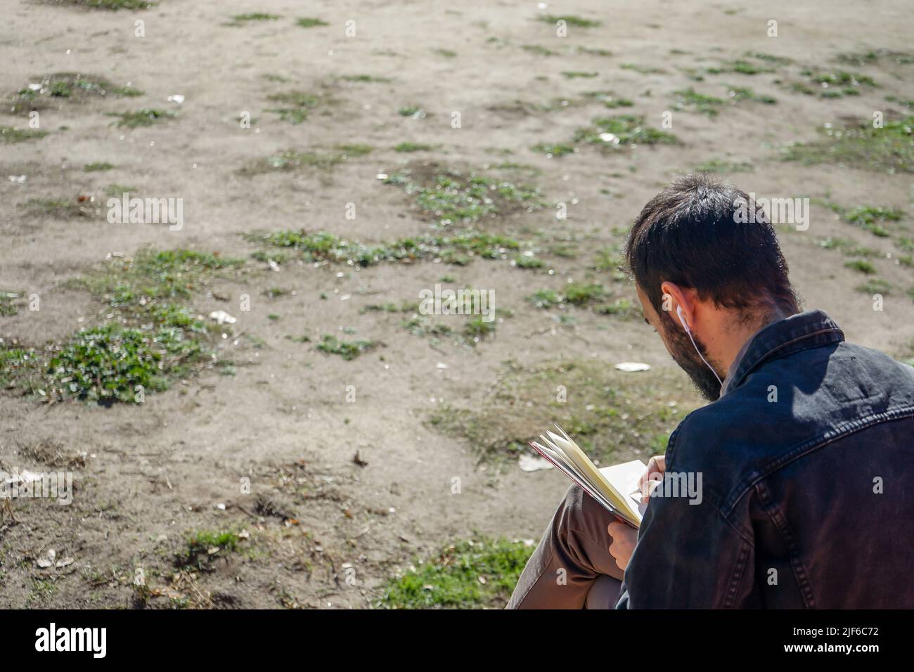 Man writing or drawing on notebook in a park. Stock Photo