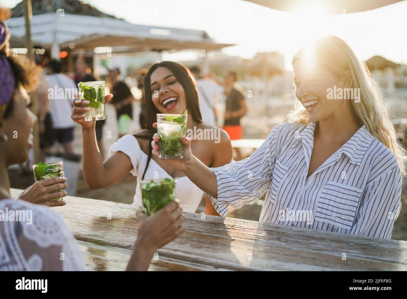 Happy girls having fun cheering with cocktails at bar on the beach - Soft focus on right girl face Stock Photo