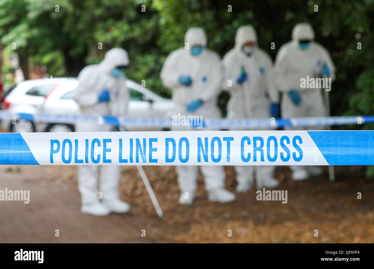 Police tape at a crime scene in the UK as scenes of crime officers seach. Stock Photo