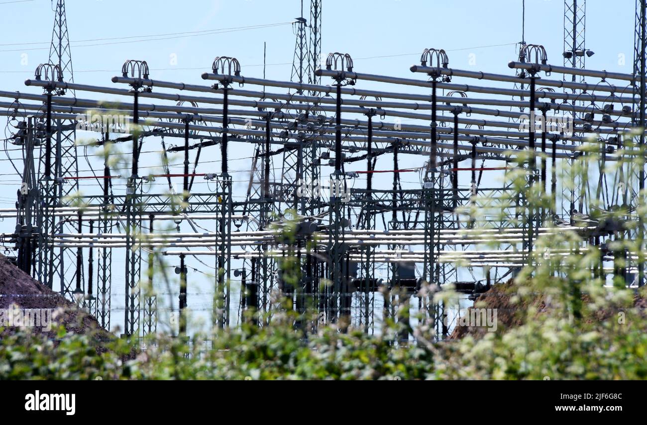 22 June 2022, Saxony-Anhalt, Bad Lauchstädt: Along a trunk road, the facilities of the Bad Lauchstädt substation can be seen standing out against the blue sky. The substation is one of over 70 electricity hubs operated by the transmission system operator 50Hertz in eastern Germany and needs to be expanded in the course of the energy transition. Two so-called STATCOMs. are being built here to collect electricity from renewable energies, transform it to a higher voltage level and transport it to other regions via extra-high voltage lines. The high-tech facilities are intended to keep the voltage Stock Photo
