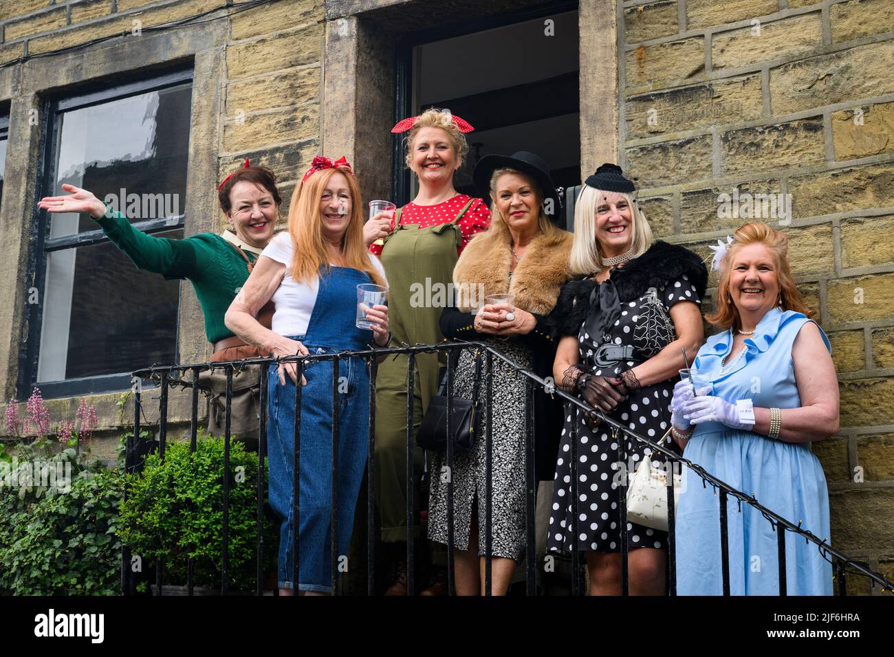 Haworth nostalgic retro living-history event (friends having fun in WW2 replica vintage outfits, posing) - Main Street, West Yorkshire, England, UK. Stock Photo