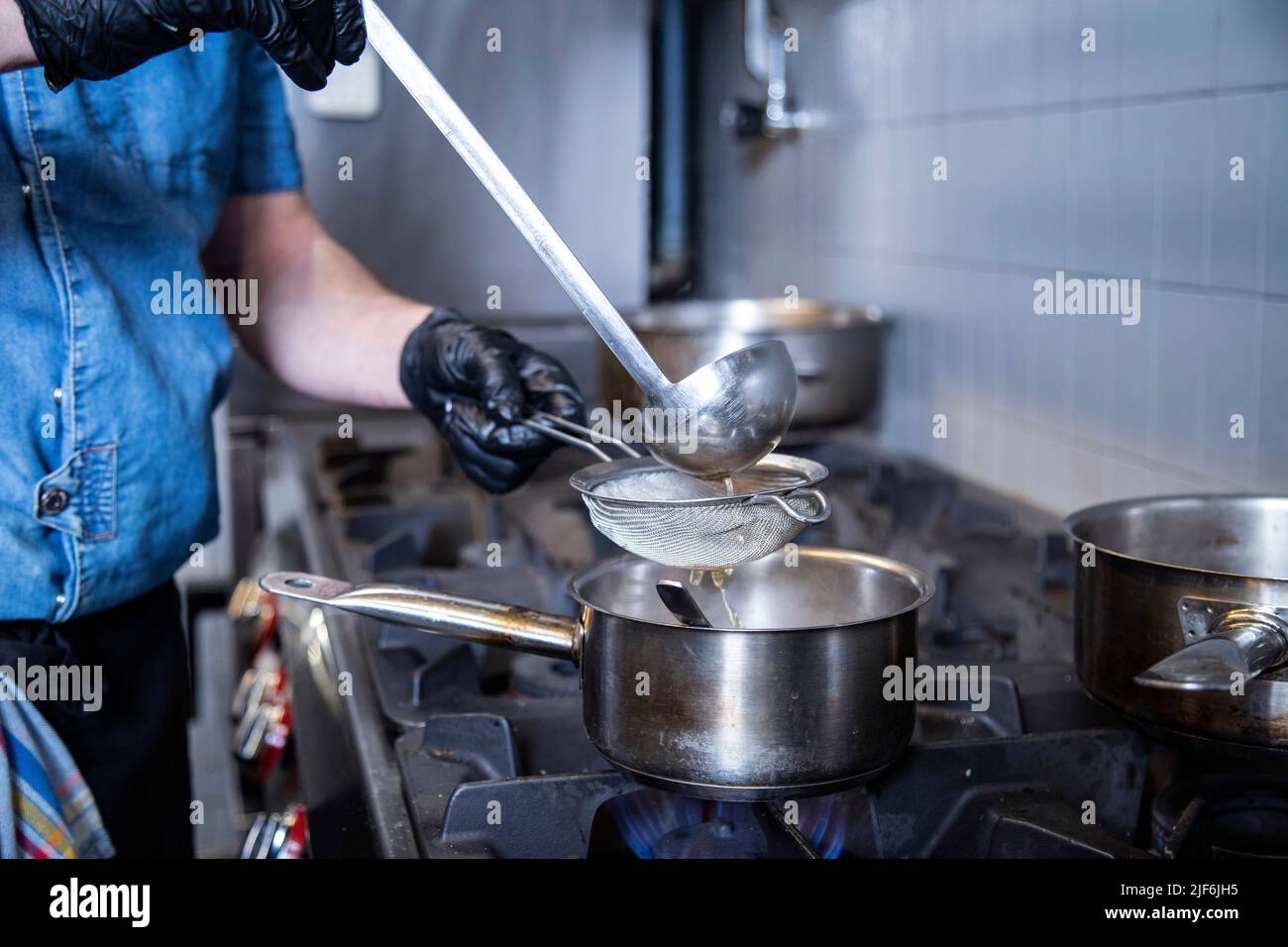 Chef separating water from rice using strainer in commercial kitchen Stock Photo