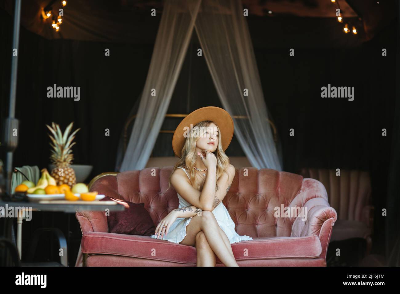 Charming barefoot female in headwear and dress looking away while ...