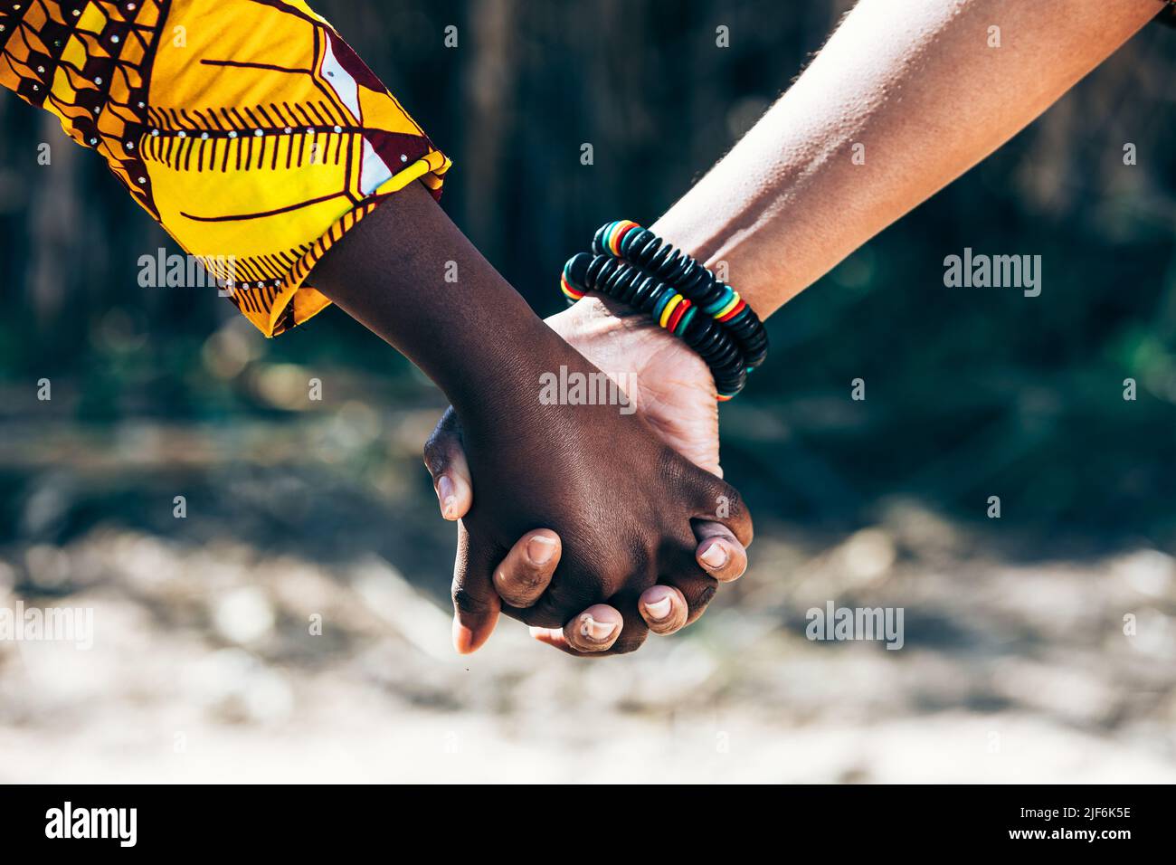 Loving multiethnic people with wooden bead bracelet holding hands and