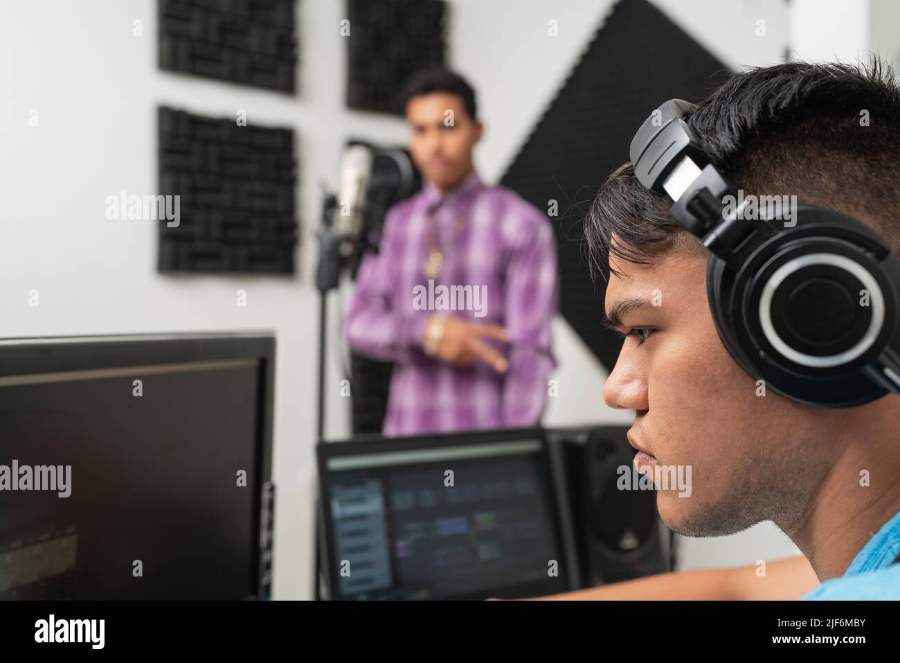 Young male singer recording voice in mic at music studio Stock Photo ...