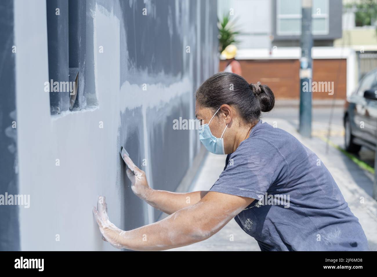 Side view of professional female painter in protective mask in process