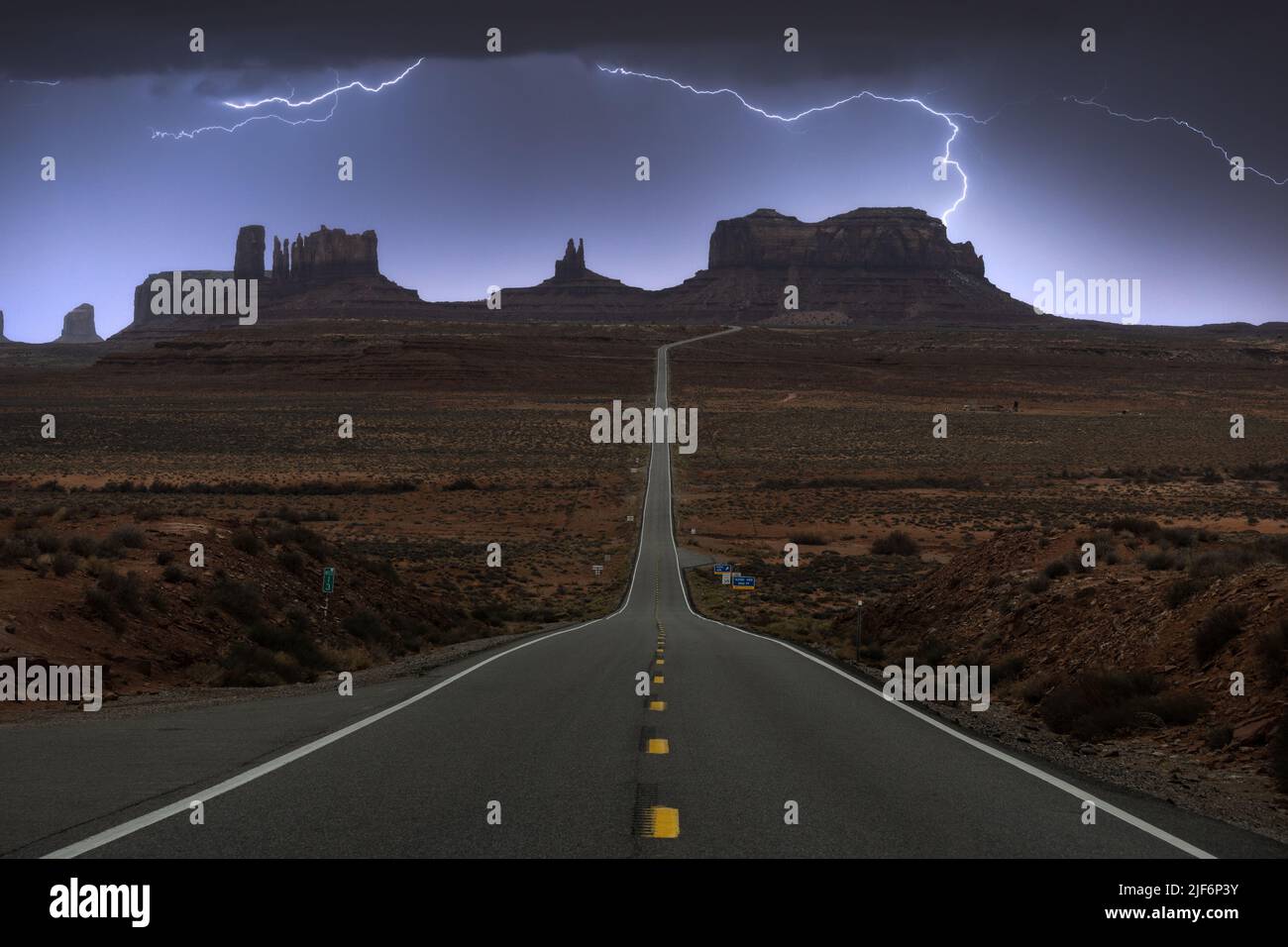 Breathtaking scenery of butte rocky outcrop formations under thunderstorm sky with clouds in between asphalt highway in Monument Valley Navajo Tribal Stock Photo