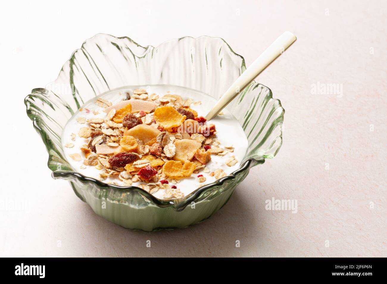 Bowl with yogurt and breakfast cereals with a metal spoon on a table Stock Photo