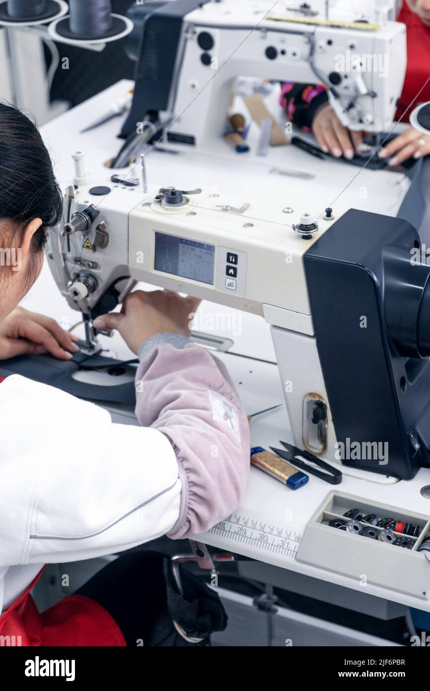 Anonymous cropped dressmakers in uniform sewing on machine while ...