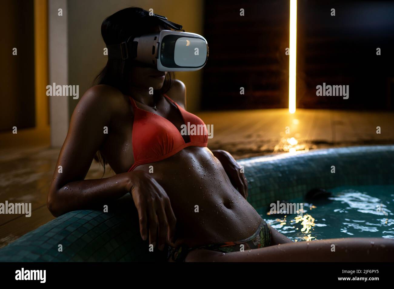 Slim African American female in bikini and modern VR goggles relaxing in  hot tub during spa procedure in evening time Stock Photo - Alamy