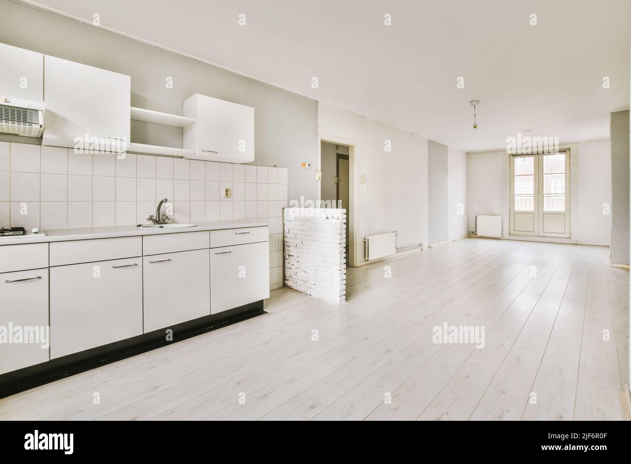 Interior of empty open plan white kitchen with windows and wooden parquet floor Stock Photo