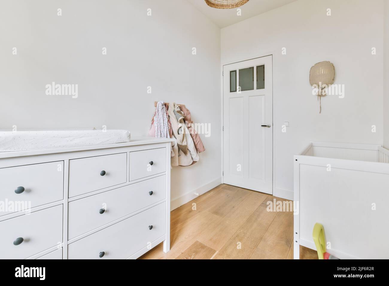 Interior of white room with baby crib and shelves near window in