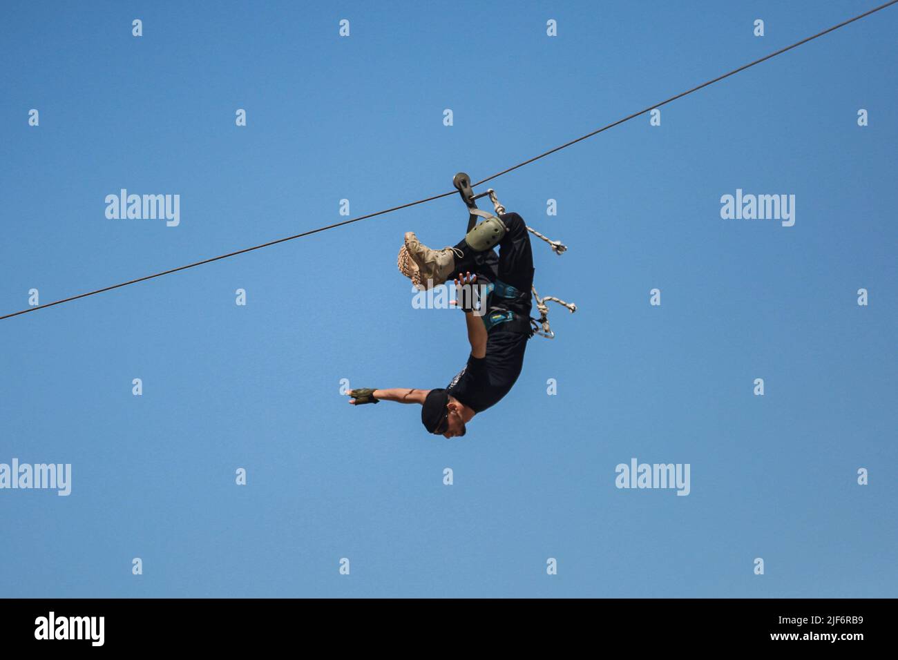 Khan Yunis, Palestinian Territories. 30th June, 2022. A member of the Palestinian Hamas security forces slides down a rope at a public graduation ceremony for police officers, during which cadets showcase their military capabilities. Hamas is intensifying military courses for its policemen to prepare them for potential confrontations with Israeli forces. Credit: Mohammed Talatene/dpa/Alamy Live News Stock Photo