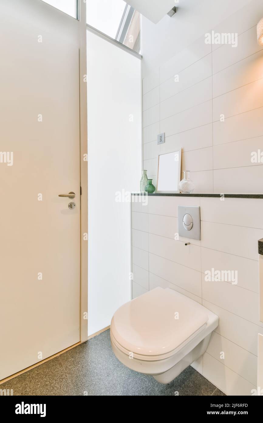 White ceramic toilet with closed lid placed between glassed wall in