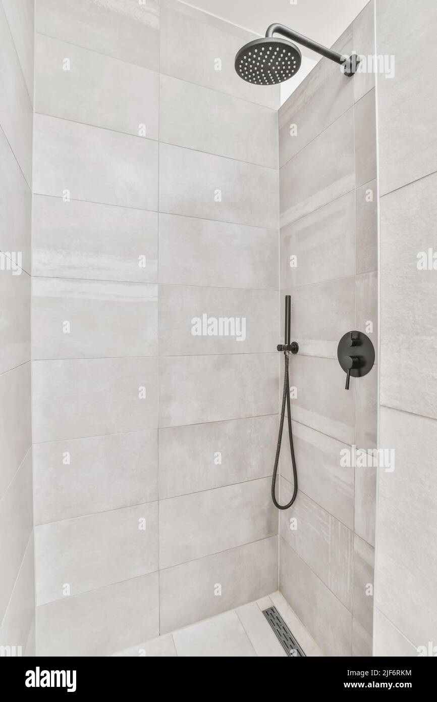 Low angle of chrome shower heads on tiled wall in spacious cabin of modern bathroom Stock Photo