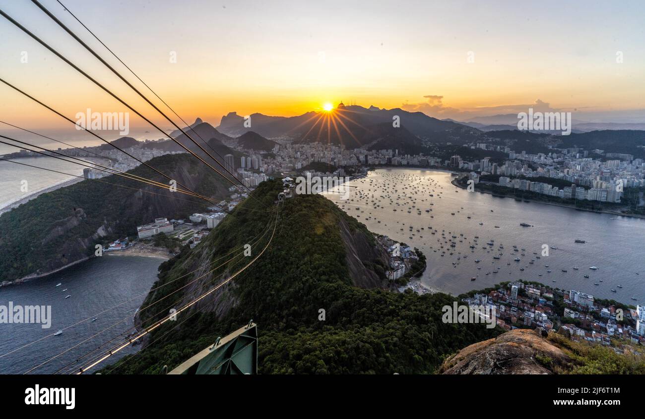 Breathtaking scenery of modern cable car riding above ocean and mountains against amazing sunset sky in Rio de Janeiro Stock Photo