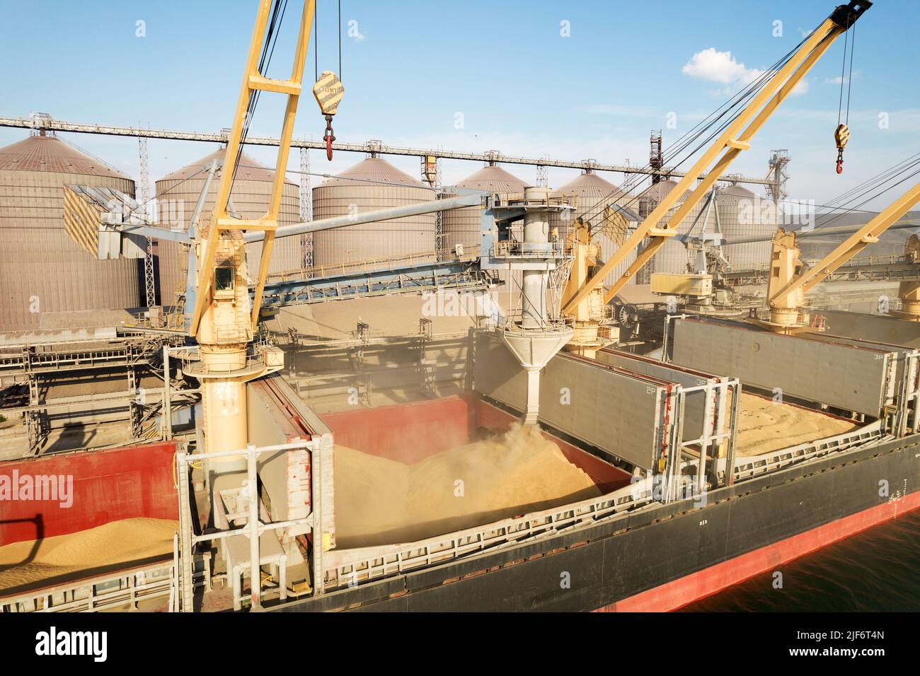 Loading grain into holds of sea cargo vessel through an automatic line in seaport from silos of grain storage. Bunkering of dry cargo ship with grain Stock Photo
