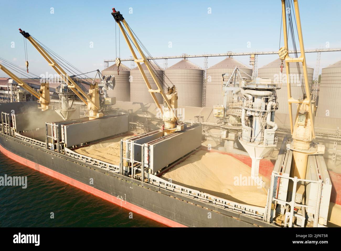 ODESSA, UKRAINE - August 9, 2021: Loading grain into holds of sea cargo vessel through an automatic line in seaport from silos of grain storage. Bunke Stock Photo