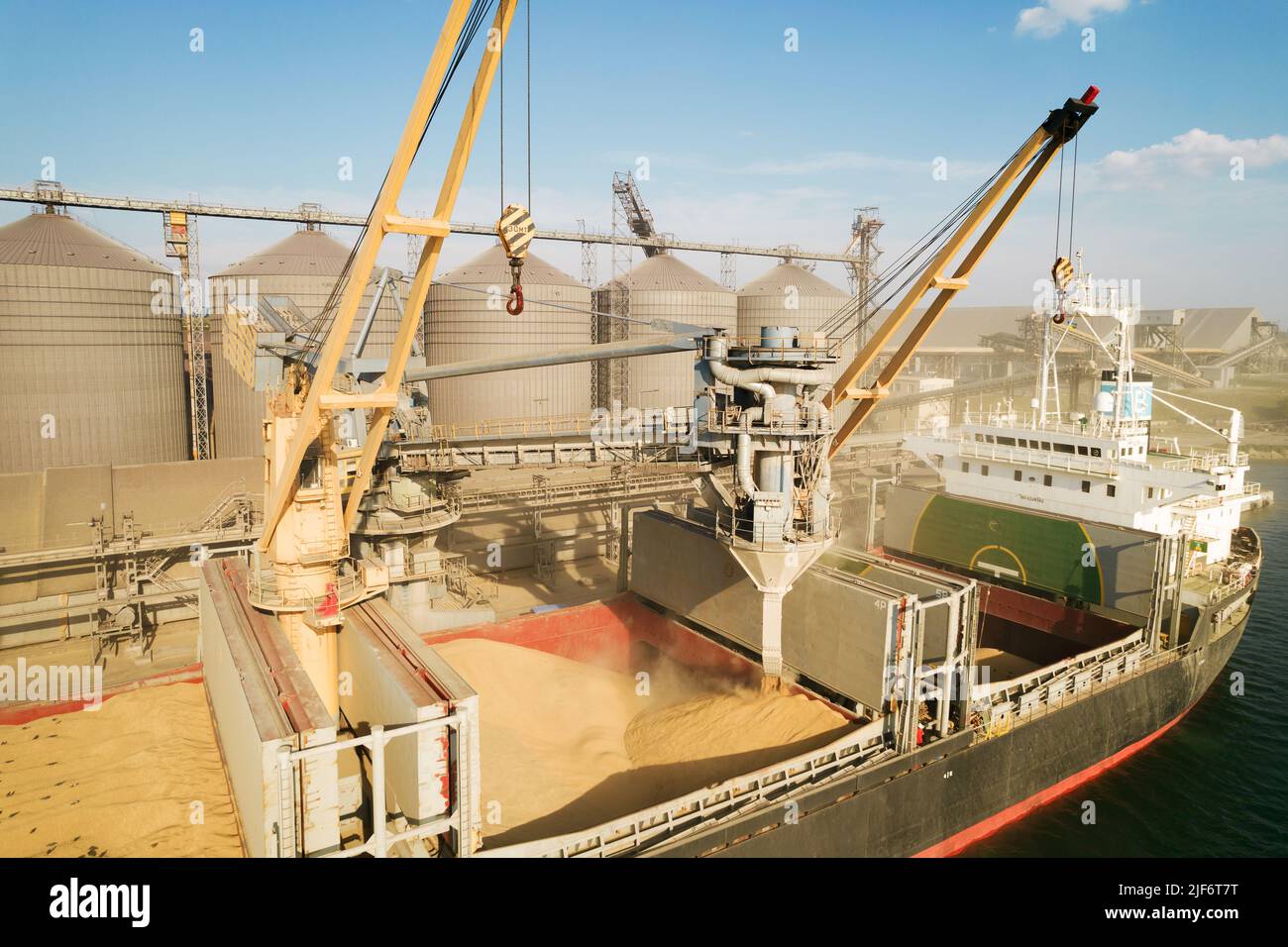 ODESSA, UKRAINE - August 9, 2021: Loading grain into holds of sea cargo vessel through an automatic line in seaport from silos of grain storage. Bunke Stock Photo