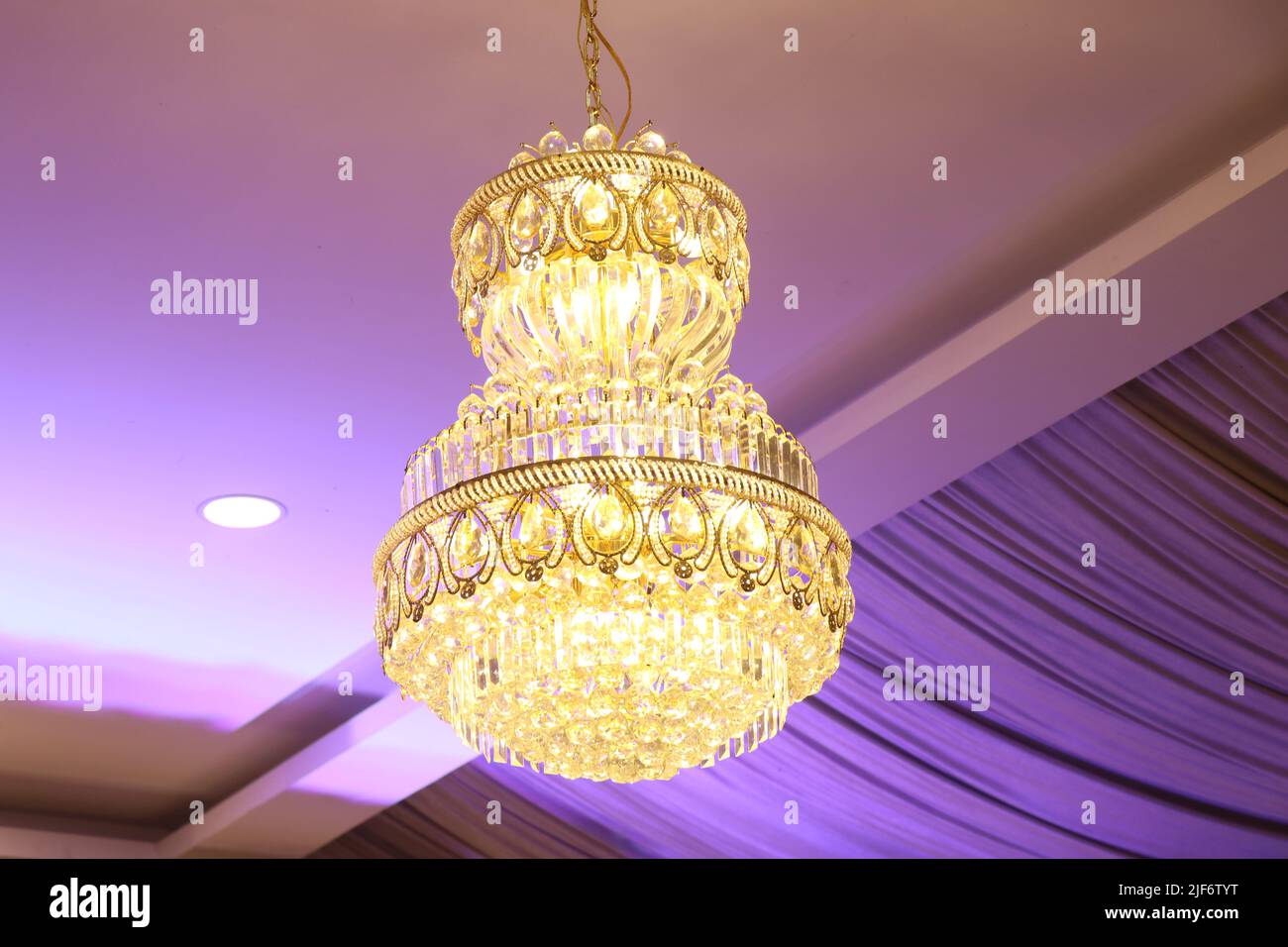 Beautiful crystal chandelier hanging from the ceiling in the interior with lights Stock Photo